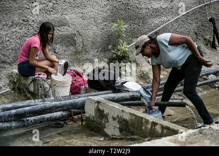 Caracas, Venezuela, Miranda. 4ème apr 2019. Une famille est considérée lave ses vêtements dans la rue en raison du manque d'eau comme ils recueillent l'eau libérée par un tuyau dans une construction abandonnée site qui contient des produits chimiques et n'est pas potable à Caracas.une nouvelle panne et manque d'eau hits Venezuela aujourd'hui qui gardent de savaging l'économie du pays ainsi que de paralyser l'industrie pétrolière qui coûtent au pays environ 200 millions de USD par jour selon les experts. Romain : crédit Camacho SOPA/Images/ZUMA/Alamy Fil Live News Banque D'Images