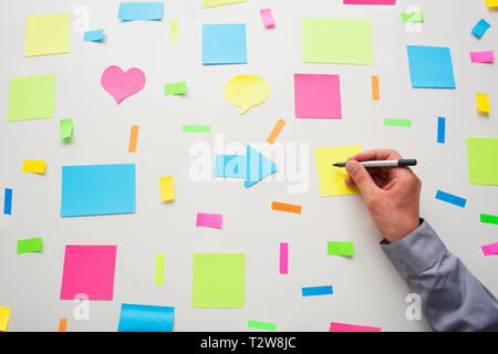 Caucasian businessman écrit sur un post-it par surround post it sur un mur Banque D'Images