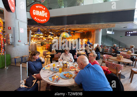 Les gens à manger cuisine monde girafe, terminal intérieur, de départs, de l'aéroport de Malaga, Malaga Espagne Europe Banque D'Images