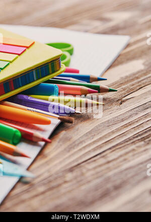 Crayons de couleur sur l'ordinateur portable sur une table en bois. L'école et les fournitures de bureau cadre . Banque D'Images