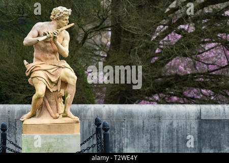 La statue en terre cuite appelée Faun joue un tuyau sur un fond d'arbres et buissons à fleurs, à la Chambre de Biltmore à Asheville, NC, USA Banque D'Images