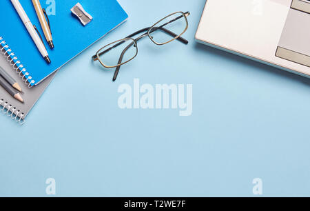 Sur un fond bleu, l'ordinateur portable de verres et les fournitures de bureau. Image fournitures scolaires et matériel de bureau Banque D'Images