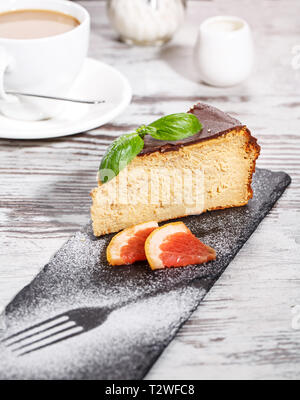 Des plats raffinés de la table dans la pièce de restaurantA cupcake à côté de deux morceaux de pamplemousse et une tasse de Cappuccino. Sur un fond clair Banque D'Images