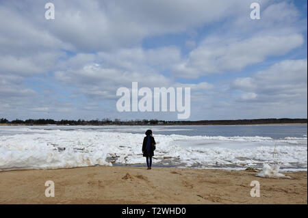 La figure d'une jeune fille dans un chapeau, debout sur la rive de la rivière Vychegda au cours de la dérive des glaces et d'admirer. Banque D'Images