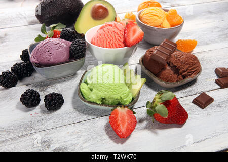 Jeu de boules de glace de différentes couleurs et saveurs de petits fruits, de chocolat et de fruits sur une table Banque D'Images