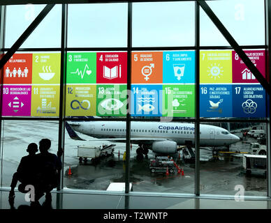 Les objectifs affichés en espagnol sur les fenêtres à Panama, l'aéroport international de Tocumen. La mère et l'enfant à la recherche pour voir les avions. Banque D'Images