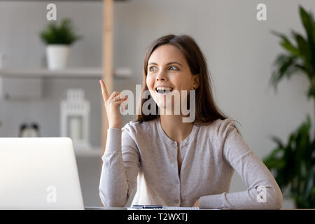 Young woman sitting at desk se sent excité avec bonne idée Banque D'Images