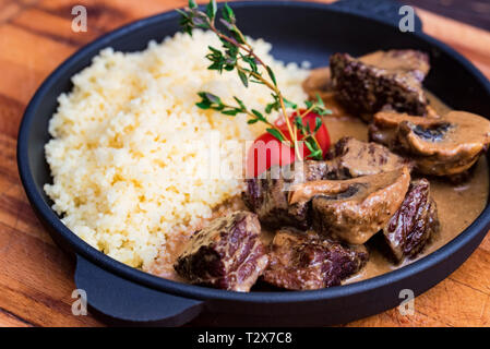 Close up poêle avec de délicieux bœuf stroganoff aux champignons et de couscous servi avec pain de seigle dans le Banque D'Images