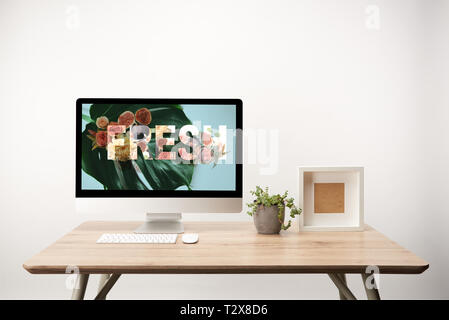 Ordinateur avec des feuilles vertes et fraîches illustration sur le moniteur sur le bureau en bois Banque D'Images