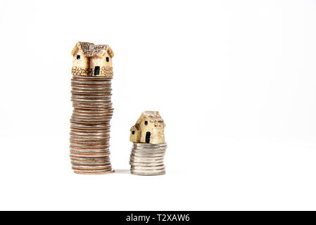Maisons miniatures sur le dessus des piles de pièces de monnaie pour représenter les différences de prix Banque D'Images