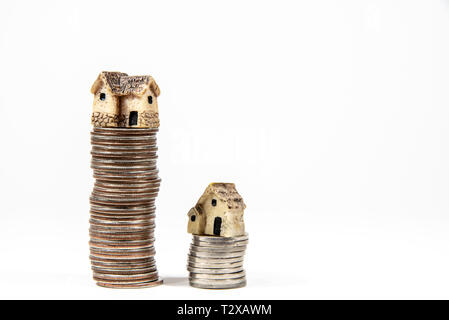 Maisons miniatures sur le dessus des piles de pièces de monnaie pour représenter les différences de prix Banque D'Images