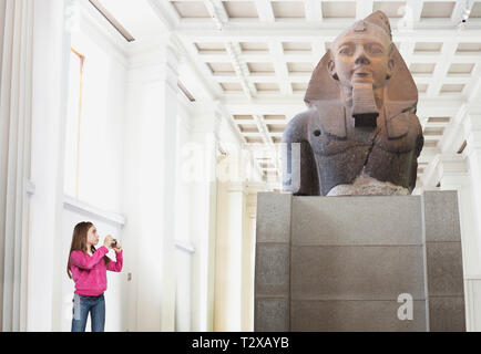 Jeune fille de photographier une statue dans un musée Banque D'Images