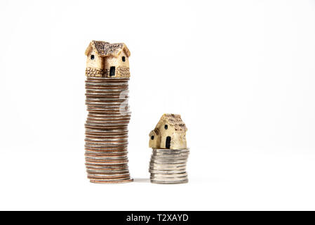 Maisons miniatures sur le dessus des piles de pièces de monnaie pour représenter les différences de prix Banque D'Images