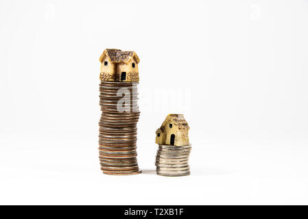 Maisons miniatures sur le dessus des piles de pièces de monnaie pour représenter les différences de prix Banque D'Images