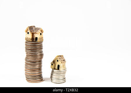 Maisons miniatures sur le dessus des piles de pièces de monnaie pour représenter les différences de prix Banque D'Images
