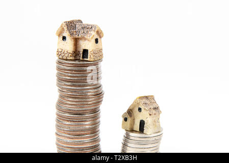 Maisons miniatures sur le dessus des piles de pièces de monnaie pour représenter les différences de prix Banque D'Images