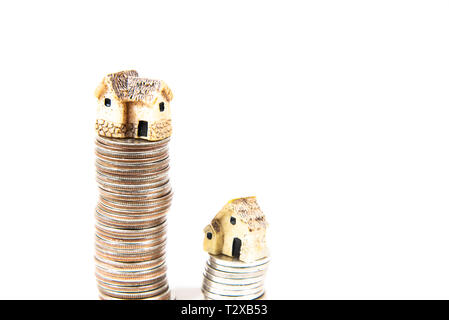 Maisons miniatures sur le dessus des piles de pièces de monnaie pour représenter les différences de prix Banque D'Images