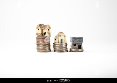 Maisons miniatures sur le dessus des piles de pièces de monnaie pour représenter les différences de prix Banque D'Images