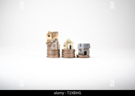 Maisons miniatures sur le dessus des piles de pièces de monnaie pour représenter les différences de prix Banque D'Images