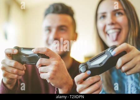 Heureux les amis à jouer aux jeux vidéo dans leur appartement hilarante - jeune couple s'amusant avec nouvelle tendance de la technologie de la console Banque D'Images