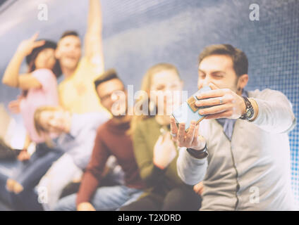 Heureux de prendre une photo d'amis en utilisant leur smartphone mobile selfies camera sitting dans un parking souterrain - groupe de population multiraciale à prendre des photos Banque D'Images