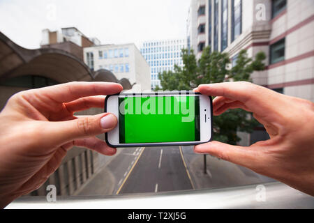Point de vue personnel d'un homme à l'aide d'un smartphone avec un écran vert Banque D'Images