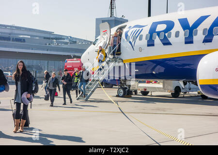 Descendre les passagers descendent de vol sur un avion de Ryanair en tirant le long de bagages à roulettes en tant que bagages à main, d'aller dans les casiers à Liverpool Banque D'Images