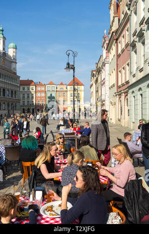 Les gens hommes et femmes assis à l'extérieur Manger et boire des cafés au soleil du printemps chaud sur la place de la vieille ville dans la ville polonaise de Poznan, Pologne Banque D'Images