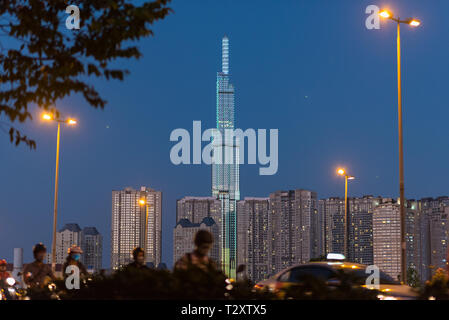 Skyline nuit Vinhomes de Central Park avec ses gratte-ciel 81 avec l'éclairage de rue et de trafic dans l'avant-plan (floue). Banque D'Images