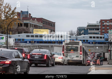 Montréal, Canada - le 9 novembre 2018 : Embouteillage sur le Boulevard St Laurent avec des voitures et un bus alors qu'un train de banlieue de Montréal est Exo Allo passant b Banque D'Images