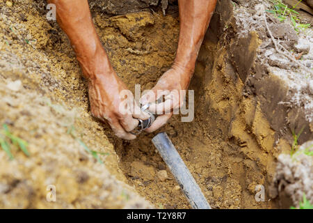 Système de gicleurs d'eau souterraine à l'homme de cour travaillant avec des tuyaux dans la masse lors de l'installation Banque D'Images