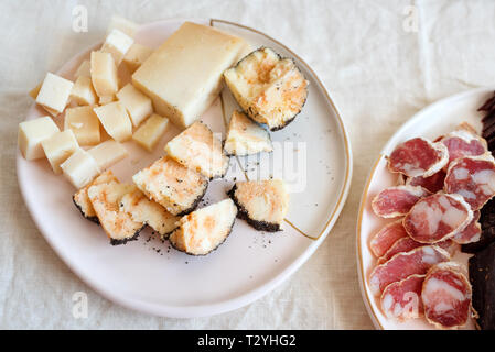 Salami et fromage, apéritifs italiens traditionnels sur fond de tissu d'un éclairage naturel. Banque D'Images