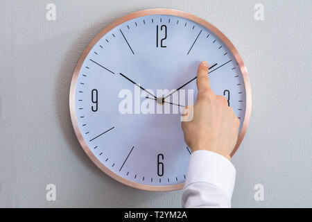 Close-up de l'homme modifie l'heure d'une horloge avec sa main Banque D'Images