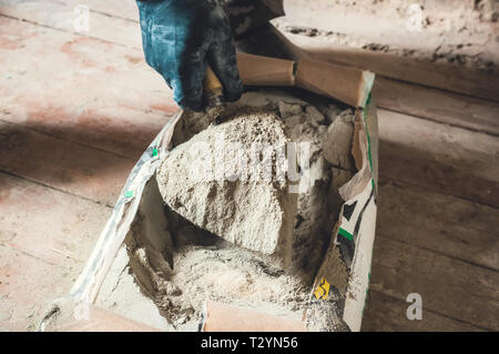 Poudre de ciment dans le sac de ciment, une main tenir la poudre de ciment écope de la truelle cray pour les travaux de construction. Banque D'Images