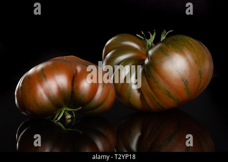 Groupe de deux ensemble de la tomate fraîche viande primora isolé sur verre noir Banque D'Images