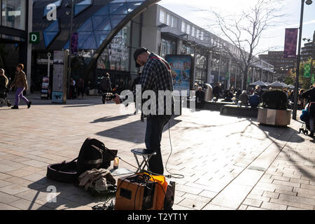 Musicien ambulant avec guitare acoustique et de l'amplificateur sur la lande palying cité commerçante piétonne, un jour d'hiver à Sheffield Banque D'Images