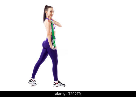 Une jeune femme coach sportif dans une salle de sport et haut court violet leggings exercice pour vos mains avec sport, bandes de caoutchouc sur un livre blanc retour isolés Banque D'Images