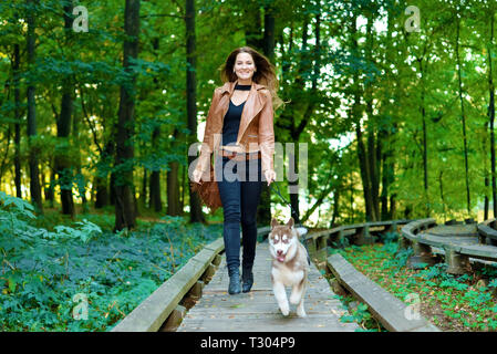 Jolie fille tourne avec chien sur pont de bois dans le parc Banque D'Images