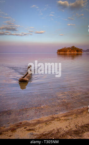 Pêcheur pousse son canoë jusqu'à la terre en tant que soleil se couche le lac Malawi Banque D'Images