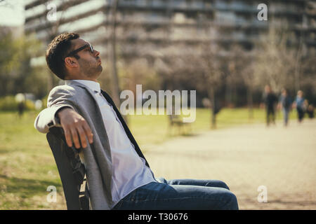Jeune homme se repose dans le parc après le travail. Banque D'Images