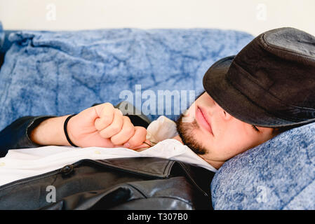 Jeune homme prendre une sieste avec un chapeau noir sur le canapé à la maison. Banque D'Images