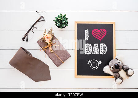 Happy Father's Day concept. Mise à plat de l'image boîte cadeau, cravate, lunettes, rose fleur et tableau sur lequel j'aime papa texte. Banque D'Images
