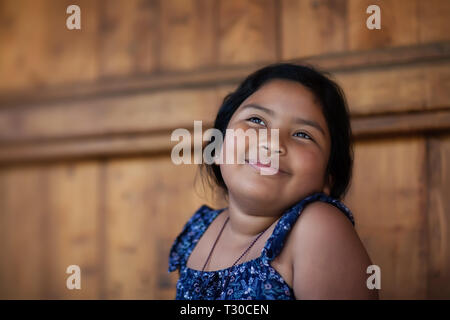 Jeune fille ethnique en souvenir d'un moment heureux dans son esprit et l'expression de la joie par un sourire et les yeux brillants. Banque D'Images