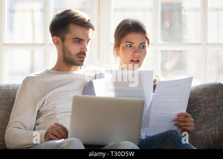 Choqué par les mauvaises nouvelles couple sitting on couch reading lettre Banque D'Images