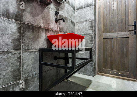 Évier Avec robinet dans rouge cher salle de bains loft dans le sport d'élite bar sur black brick wall background Banque D'Images