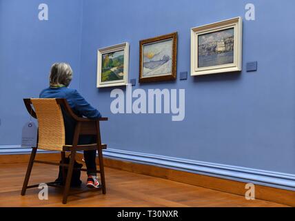 04 avril 2019, la Thuringe, Weimar : Un visiteur regarde les photos (r-l) 'Vue de Constantinople" (Paul Baum), 'Winter Sun' (Henry van de Velde) et 'Summer Parkweg près de Pretzfeld Château' (Curt Herrmann) dans le Neues Museum Weimar, prises le jour avant la réouverture, en même temps que l'ouverture du nouveau Musée du Bauhaus le 5 avril 2019. Dans le Neues Museum l'exposition 'Van de Velde, Nietzsche und die Moderne um 1900' s'affiche, ce qui correspond à la présentation dans le Musée du Bauhaus. L'accent est mis ici sur la préhistoire du Bauhaus avec des œuvres de réalisme, l'impressionnisme et l'Art Banque D'Images