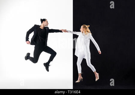 Tenant la main. Blonde model wearing long chemisier blanc tenant la main de son collègue en costume noir Banque D'Images