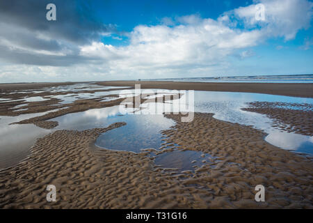 Motifs faits par des bassins de marées d'eau à marée basse sur la plage de Burnham Overy Staithe sur la baie de Holkham, la côte nord de Norfolk, East Anglia, Angleterre, Royaume-Uni. Banque D'Images