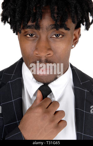 Un close up image d'un homme en costume noir et chemise blanche et cravate fixant sa cravate avec fussy cheveux noirs, isolés pour fond blanc Banque D'Images