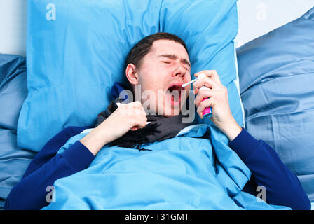 Image de l'homme malade de l'éternuement en écharpe et avec les mouchoirs dans la main au lit . Banque D'Images